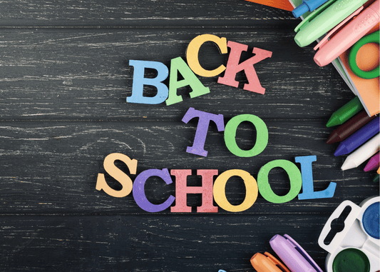 black background with school supplies like markers and scissors on the side with the words back to school in magnetic letters in different colors - blue, purple, yellow, green