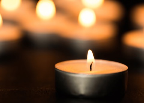 Lit candle glowing softly in a dark, peaceful setting
