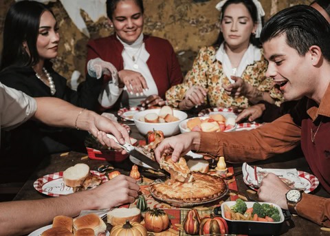 family/friends gathered around the Thanksgiving table "digging in"