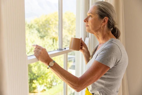 a woman with a cup of coffee looking out a window