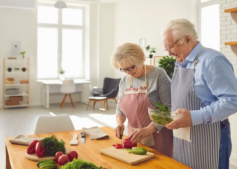 an older man and woman cooking in the kitchen together