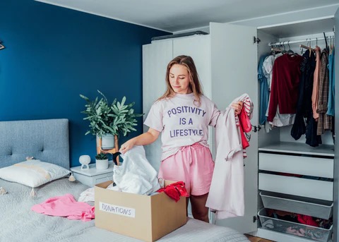 a woman going through her closet and sorting out what to keep, what to donate, and what to trash