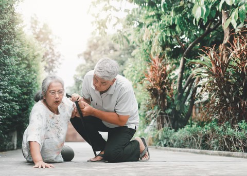 a woman has fallen on the ground. a man is helping her up