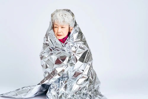 emergency blanket wrapped around an older woman
