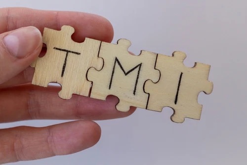 a woman holding three puzzle pieces linked together with the letters TMI