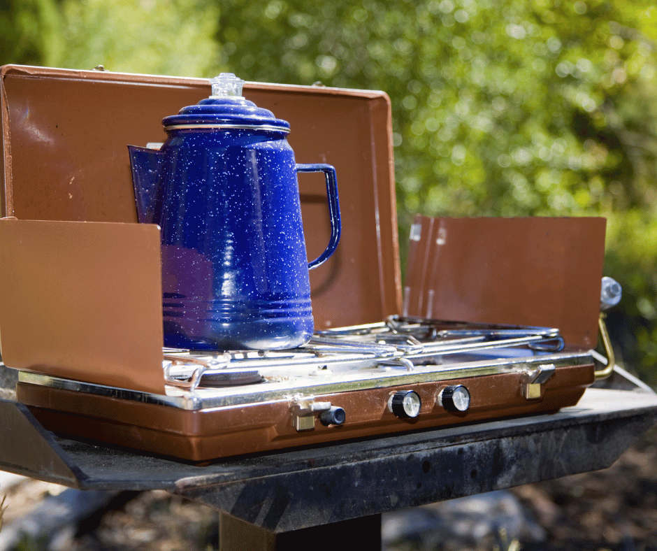 a two burner camping stove with a pot of coffee "cooking"