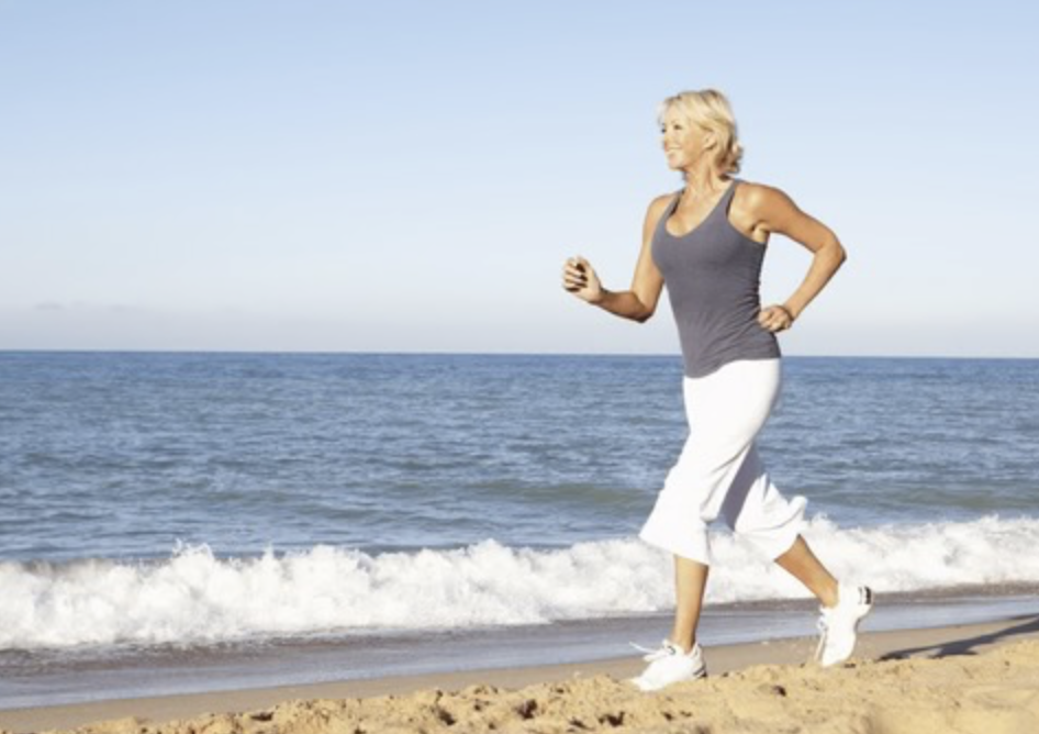 Older woman walking along the beach for exercise
