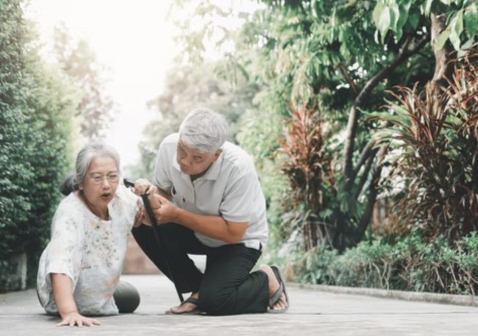 Older woman being helped after falling outdoors.